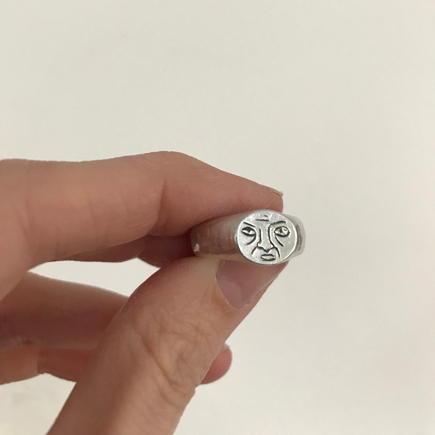 silver signet ring with a grumpy face 